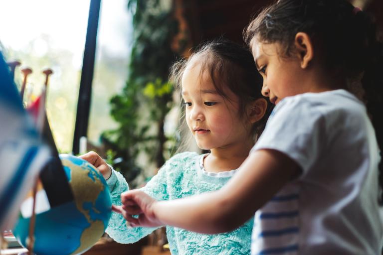 Children pointing at countries on a globe